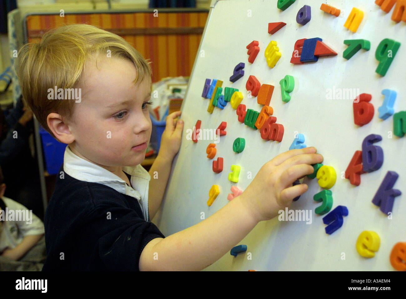 kleiner Junge spielt mit Brief Magnete im Kindergarten Stockfoto