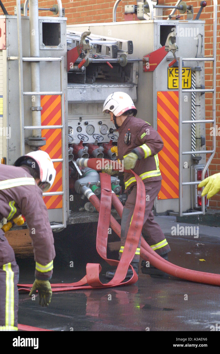 Feuerwehrleute, die Verbindungsschläuche an das Wassernetz Stockfoto