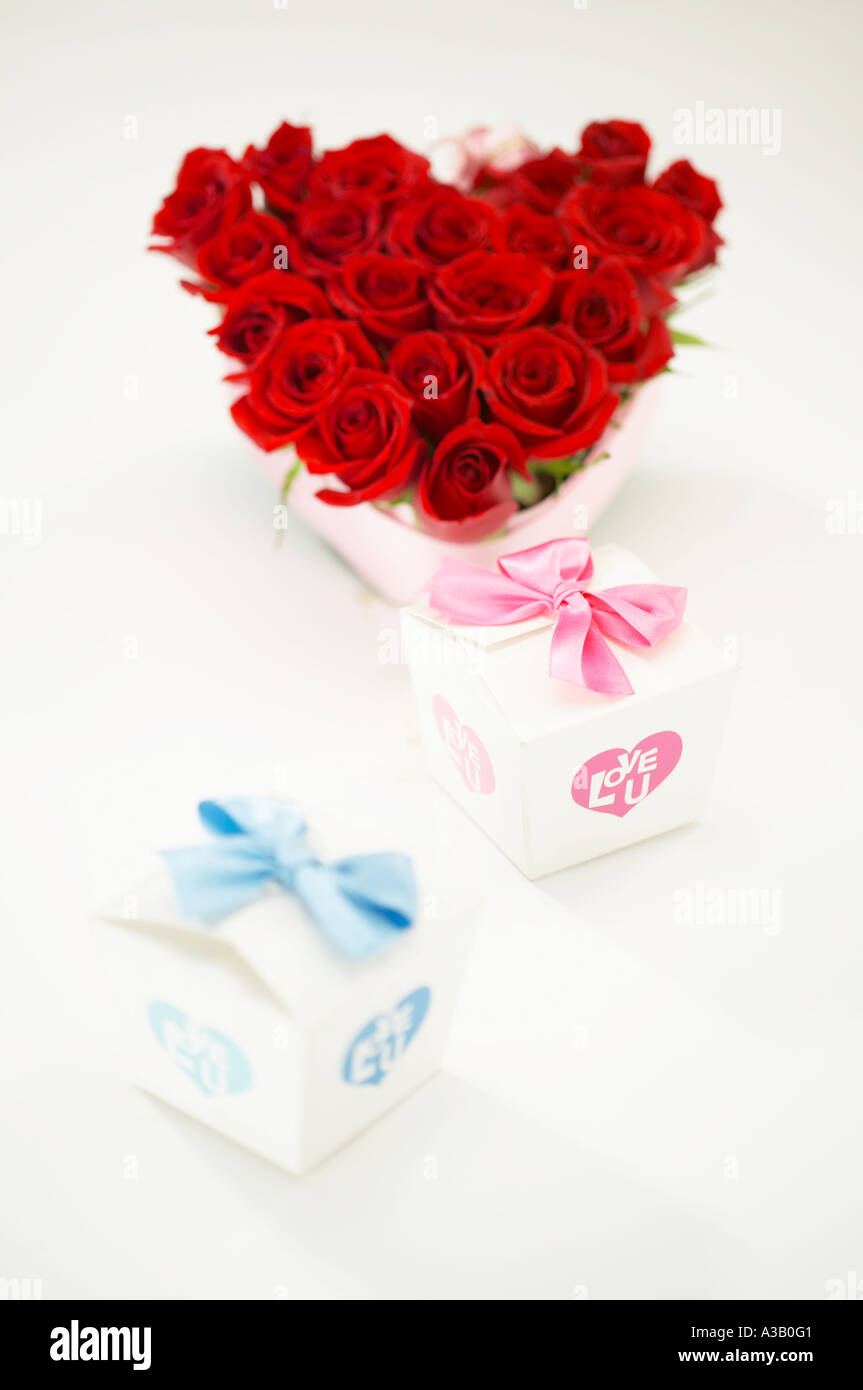 Rote Rosen in Herzform und zwei kleine Geschenk-Boxen angeordnet Stockfoto
