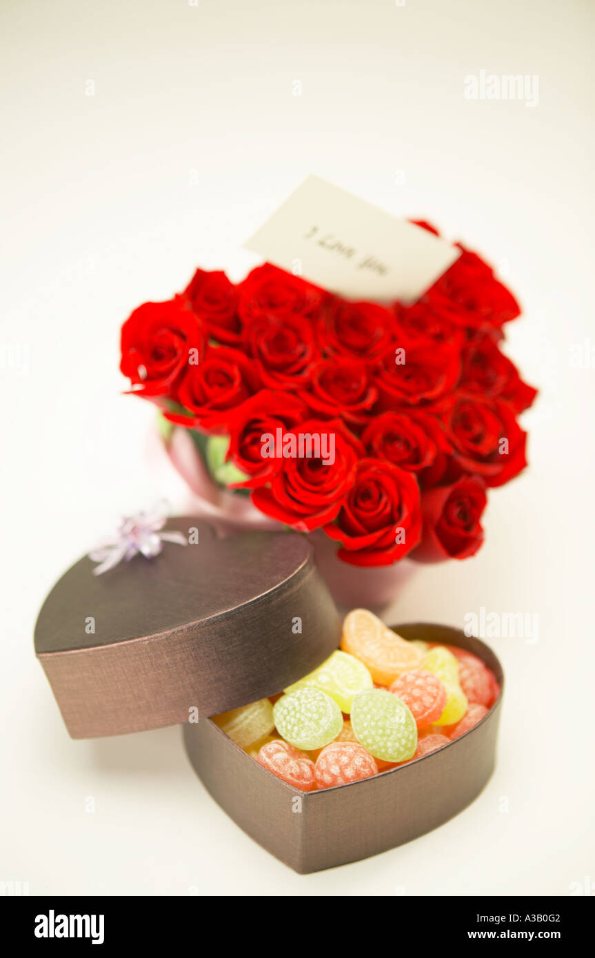 Rote Rosen in Herzform und eine Schachtel Bonbons angeordnet Stockfoto
