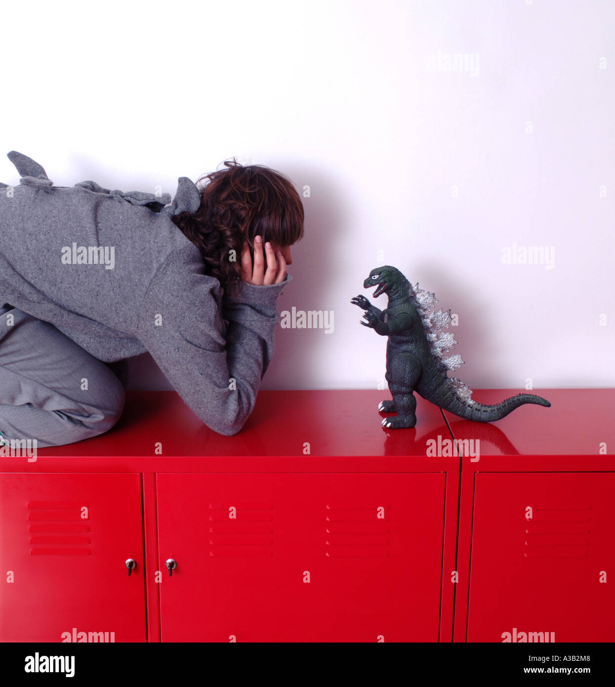 Mädchen in grauen Outfit mit Dinosaurier Zacken auf dem Rücken grün