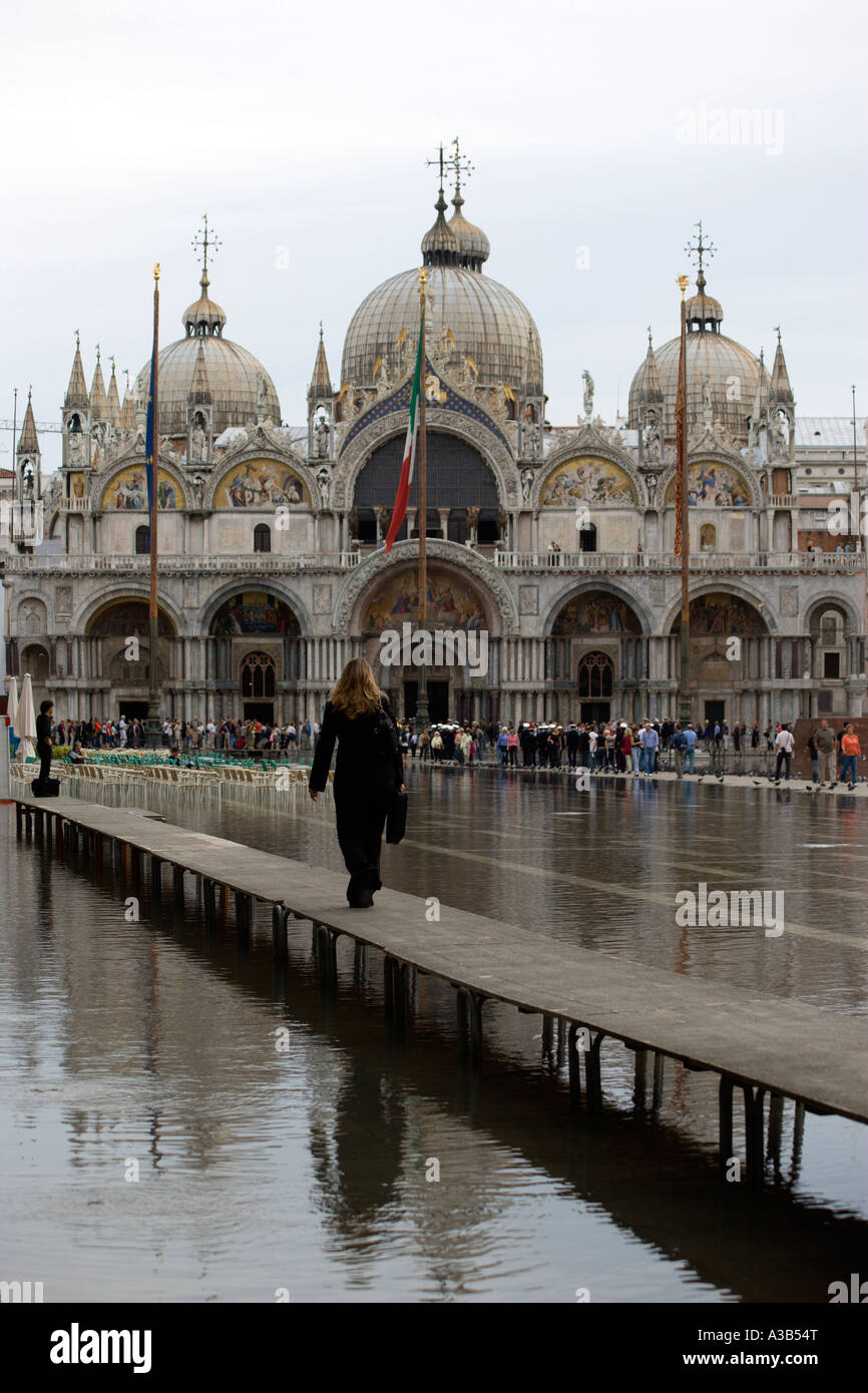 Italien Venetien Venedig Aqua Alta Hochwasser Überschwemmungen St. Mark's Square Frau auf erhöhten Gehweg auf der Piazza mit Basilika Stockfoto