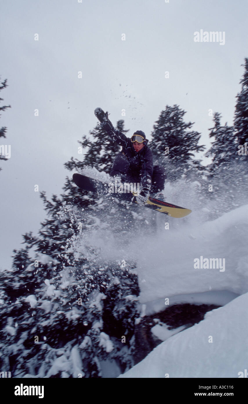 Snowboarder springt durch Wald Stockfoto