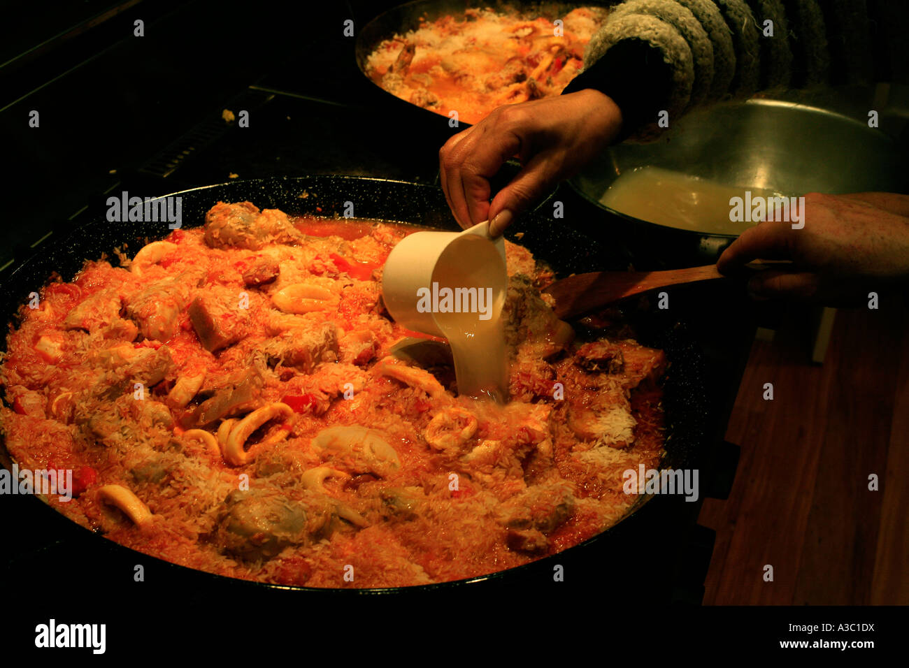 Lager wird eine Paella hinzugefügt, wie es Köche Stockfoto