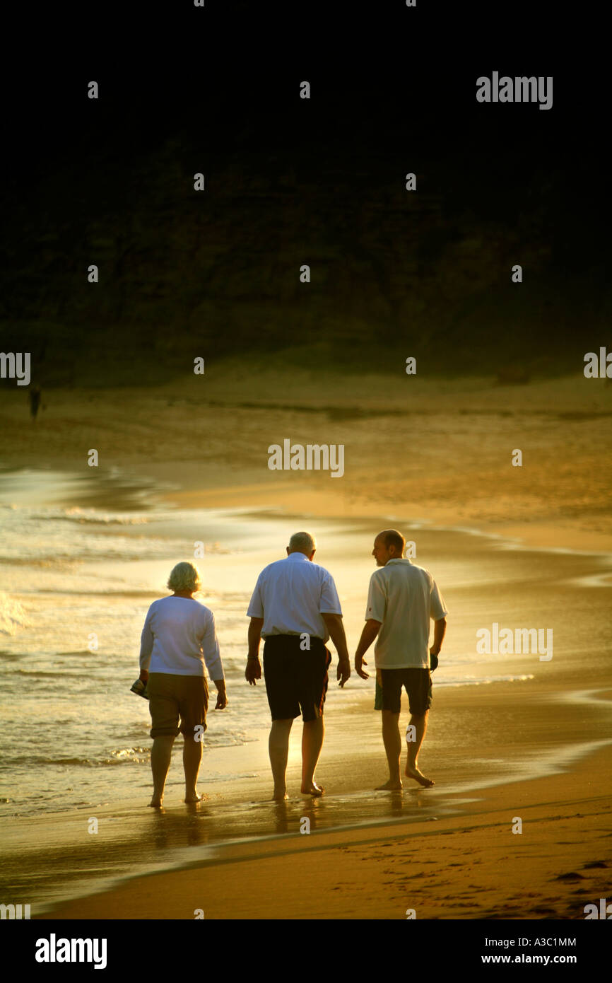 Drei Menschen gehen zusammen am Strand bei Sonnenuntergang in Australien Stockfoto