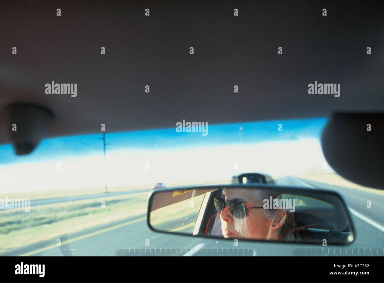 Reflexion der Fahrerin gesehen durch den Rückspiegel Fahrt entlang Highway 84 in Lubbock TX Stockfoto