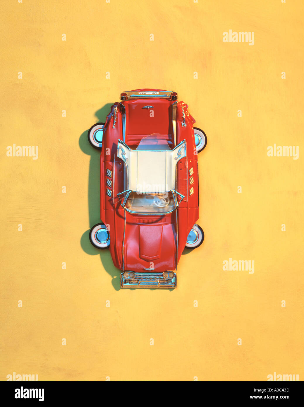 Flache rote Spielzeugauto auf gelbem Hintergrund, der von Peter McArthur, 1993 Stockfoto