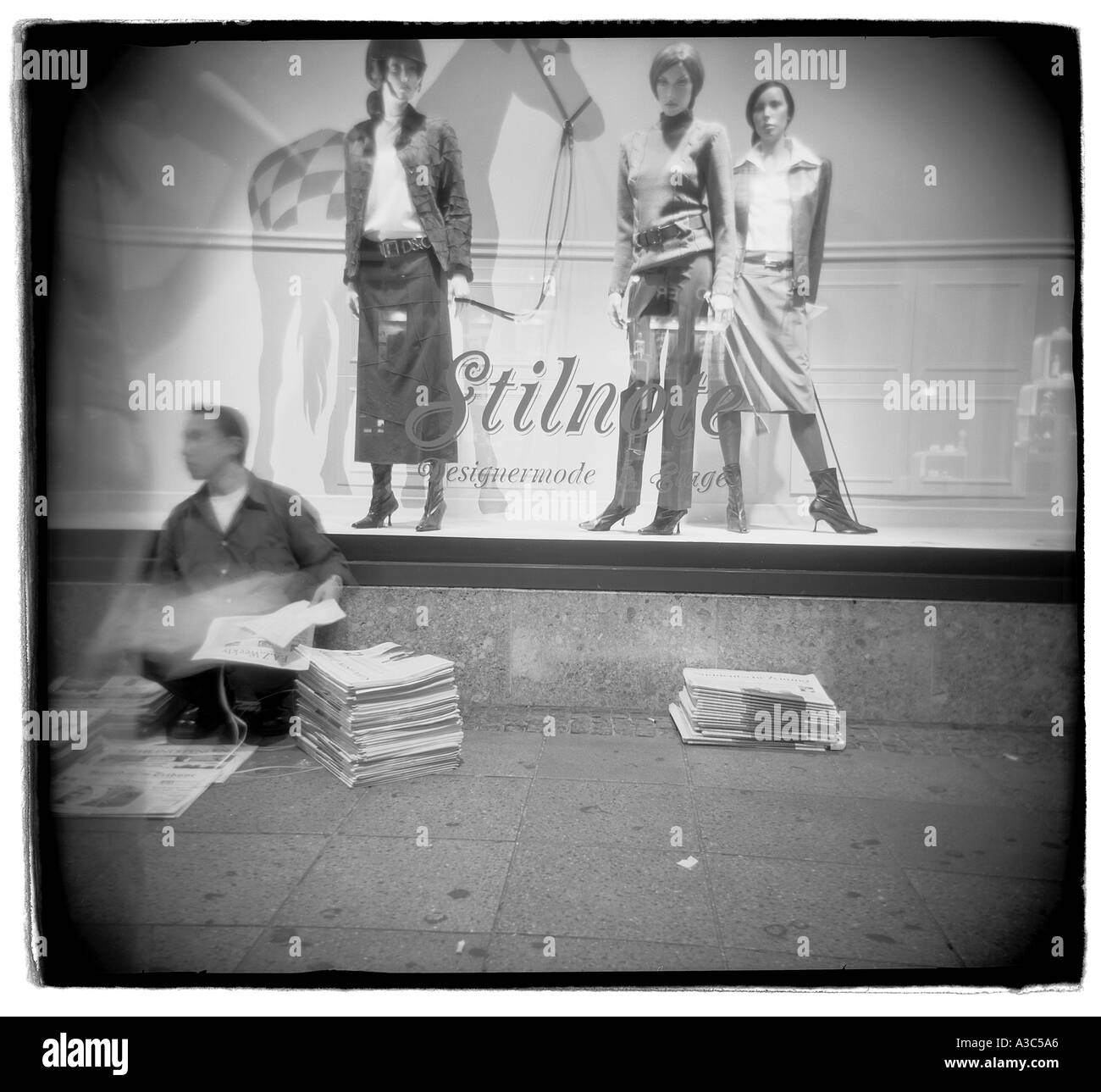 Zeitung-Verkäufer sitzen in Fornt Store-Fenster mit Puppen auf dem Display München Stockfoto