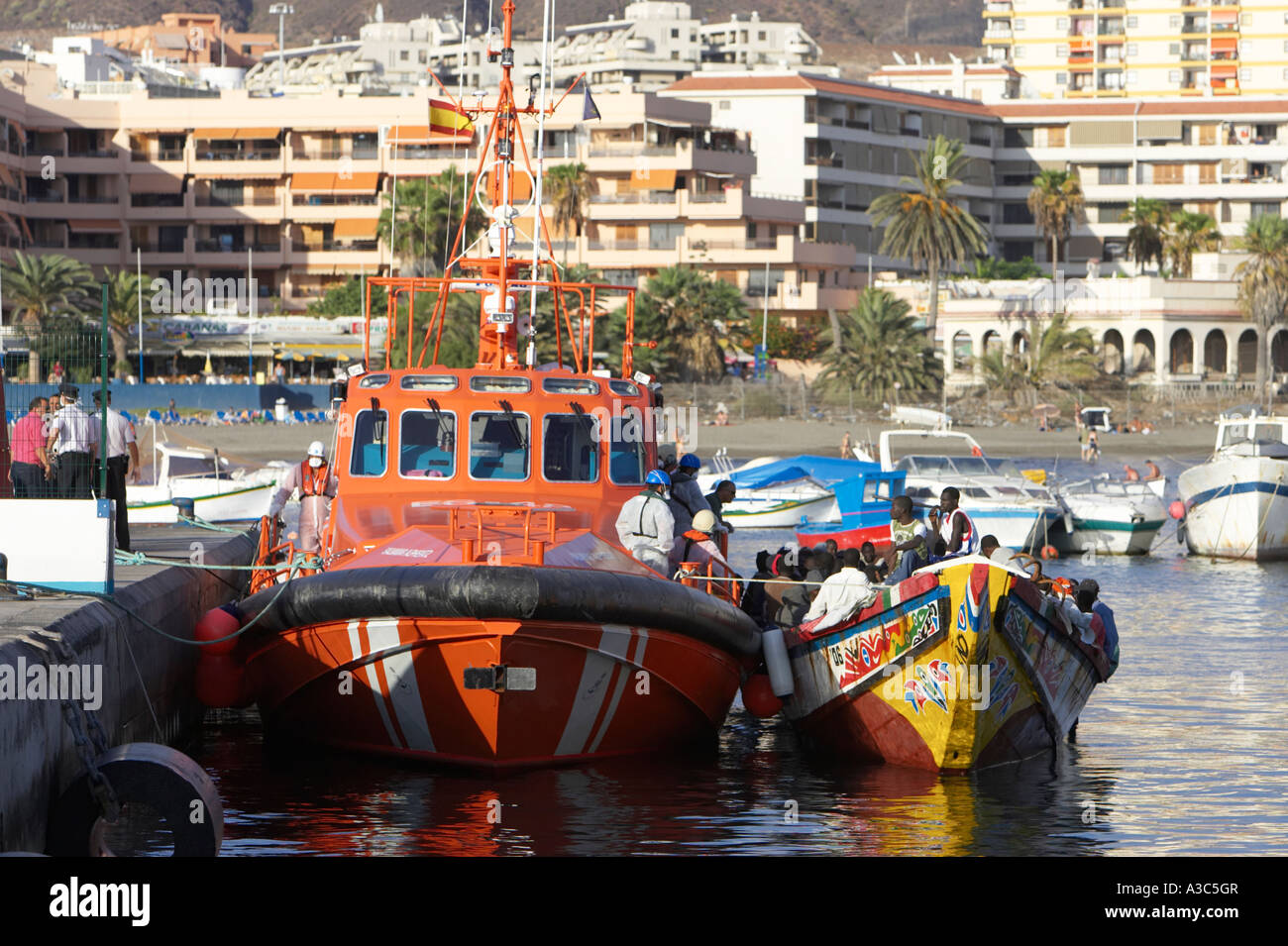 die spanische Polizei und Beamte in Schutzkleidung und Masken auf orange Maritimo Salvamento Boot entfernen illegaler Einwanderer Stockfoto