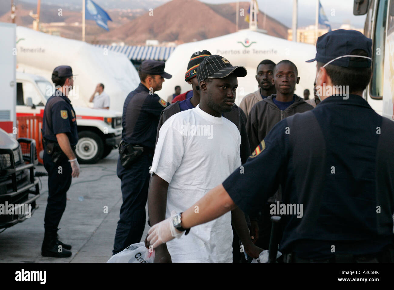 Die spanische Polizei in die Prävention, Handschuhe und Masken escort illegale Einwanderer aus Nordafrika kam gerade mit dem Boot Los Christianos Stockfoto