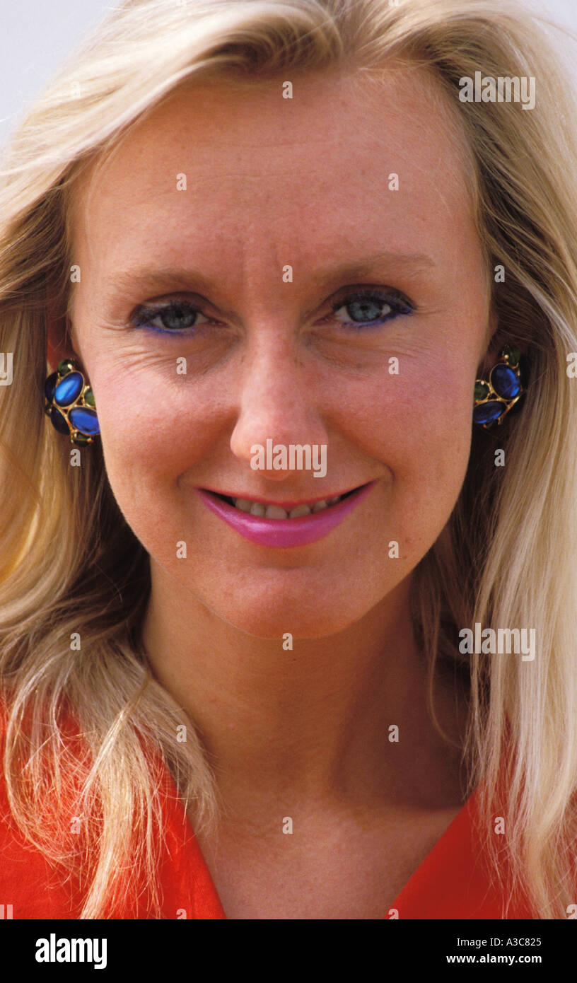 Eine attraktive Blondse Frau ist gesehen, trägt blaue Ohrringe und eine rote Bluse Purcell-Team Stockfoto