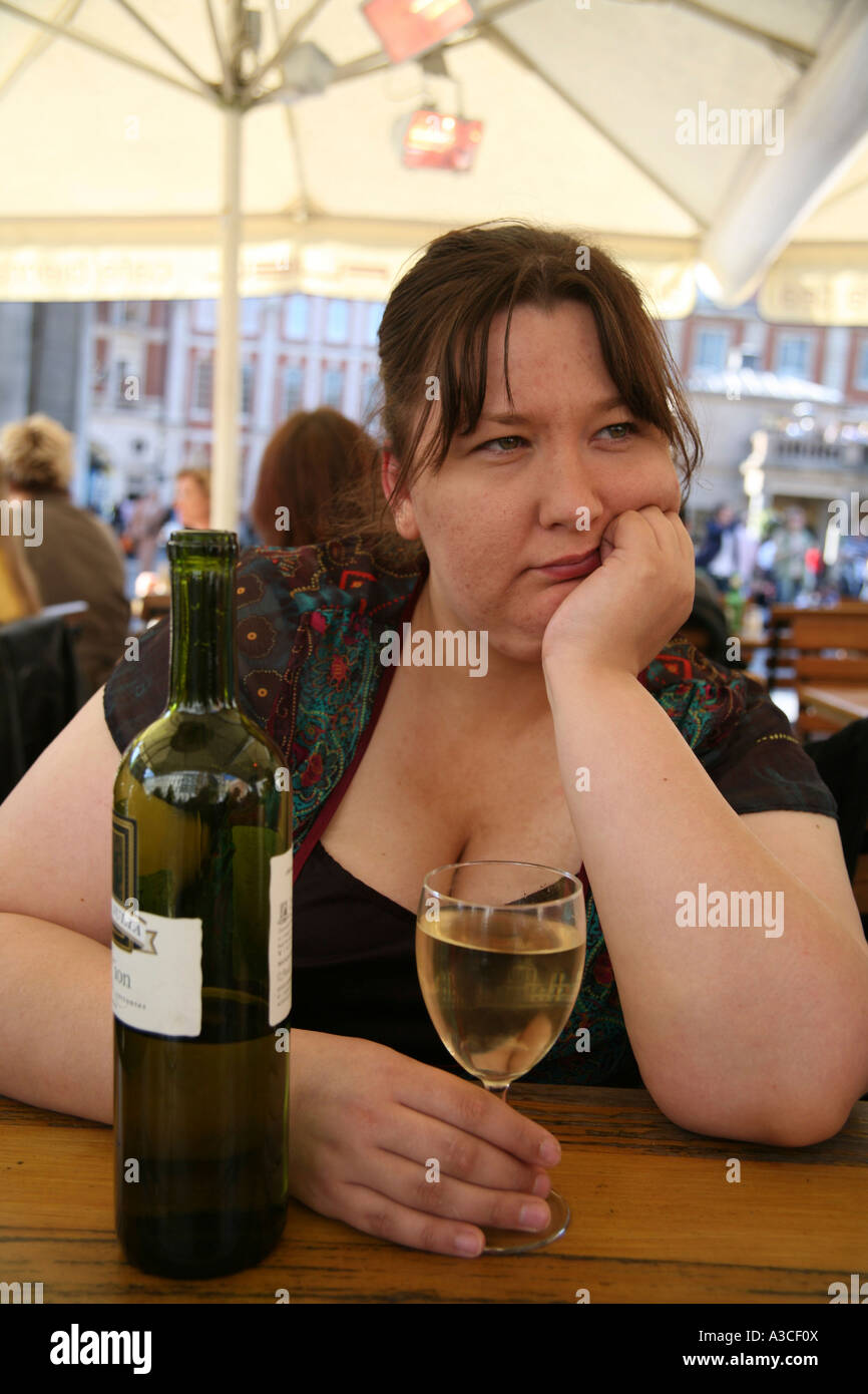 rundliche Frau mit einer Flasche Wein auf der Suche deprimiert Stockfoto