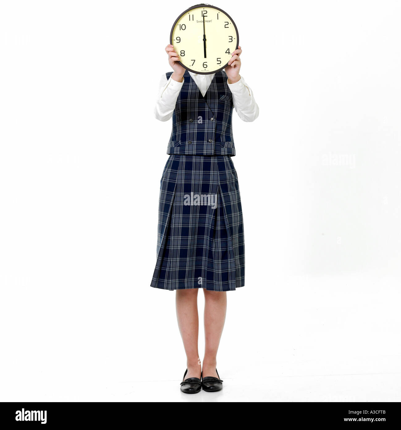 Eine Mädchen in Schuluniform ist eine Uhr vor ihr Gesicht halten. Stockfoto