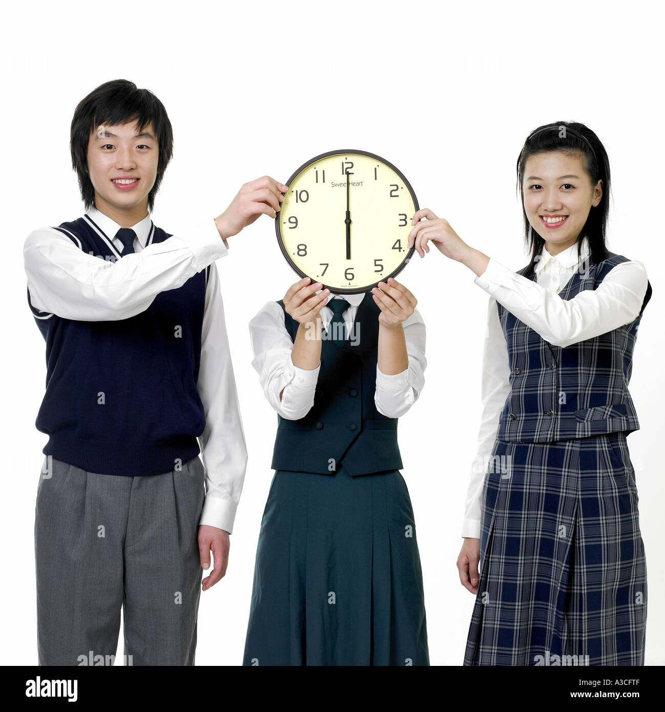 Drei Studenten halten eine Uhr zusammen Stockfoto