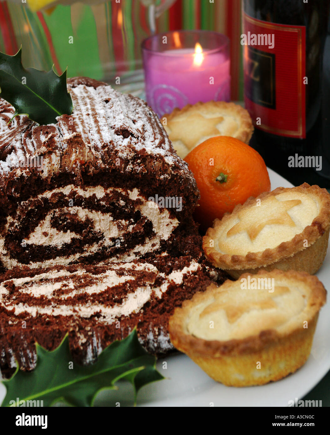 traditionelle Schokolade Bûche und Mince Pies mit Kerze Stockfoto