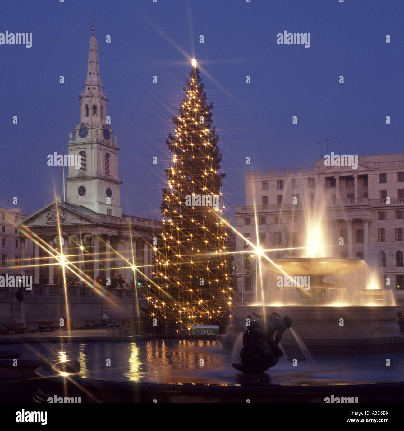 Wasserspiel im Trafalgar Square London England UK & Weihnachtsbaum Lichter mit Flutlicht am Brunnen & St. Martin in die Felder Kirche & Turm Stockfoto