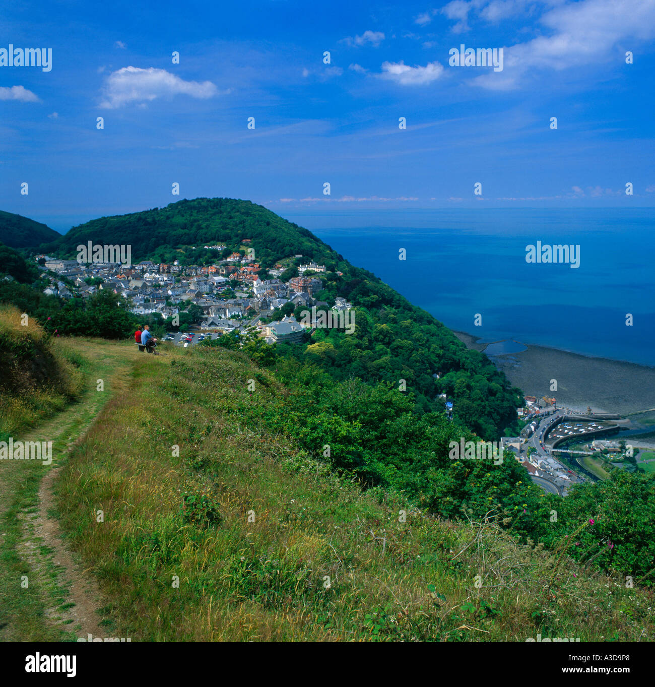 Ferne paar auf Pfad auf Sommerhaus Hügel oberhalb Lynmouth und Lynton und kleine Boote im Hafen von North Devon England Stockfoto