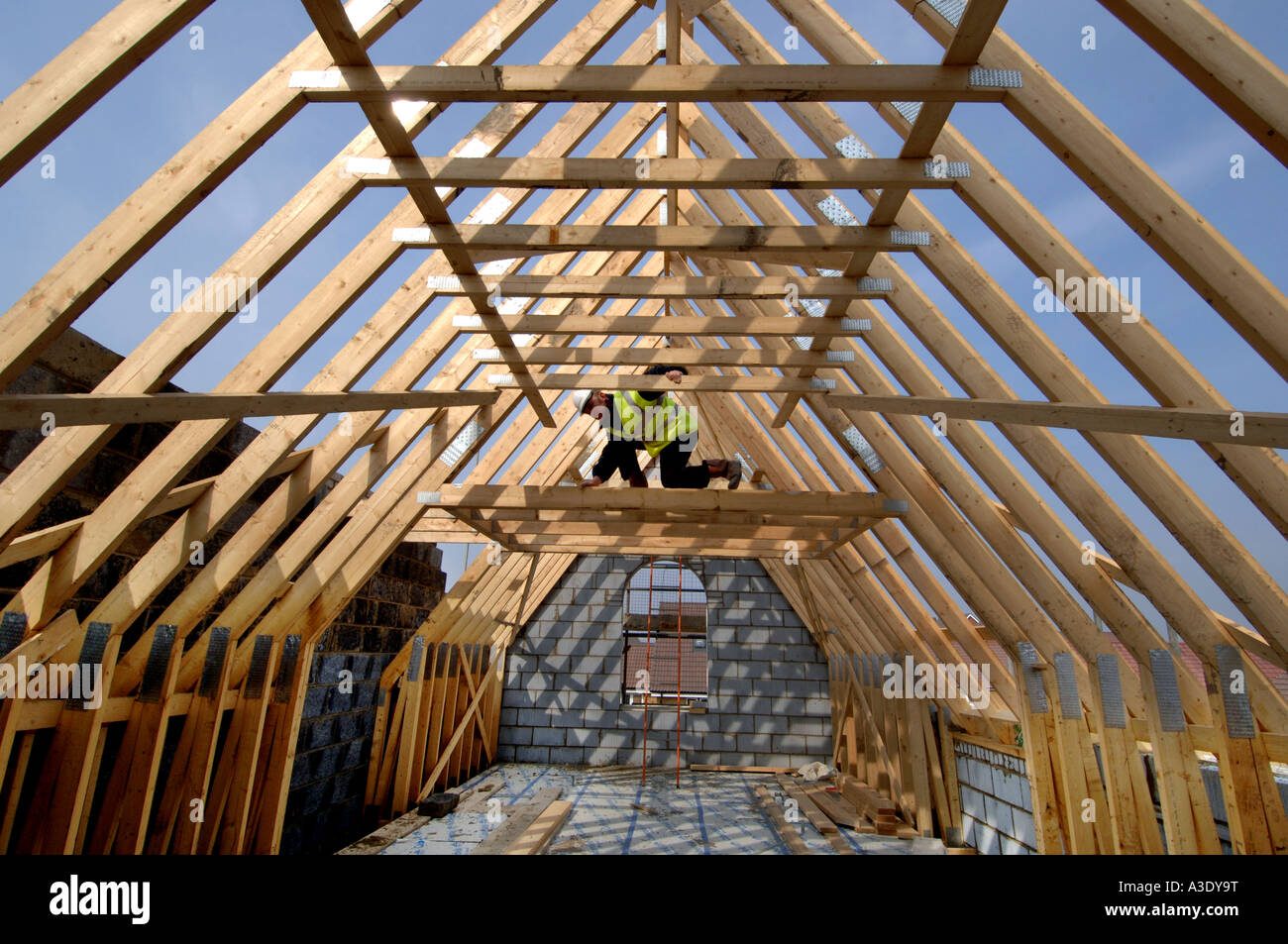 Ein Baumeister Vermessung der Dachstuhl eines neuen Hauses im Bau. Stockfoto