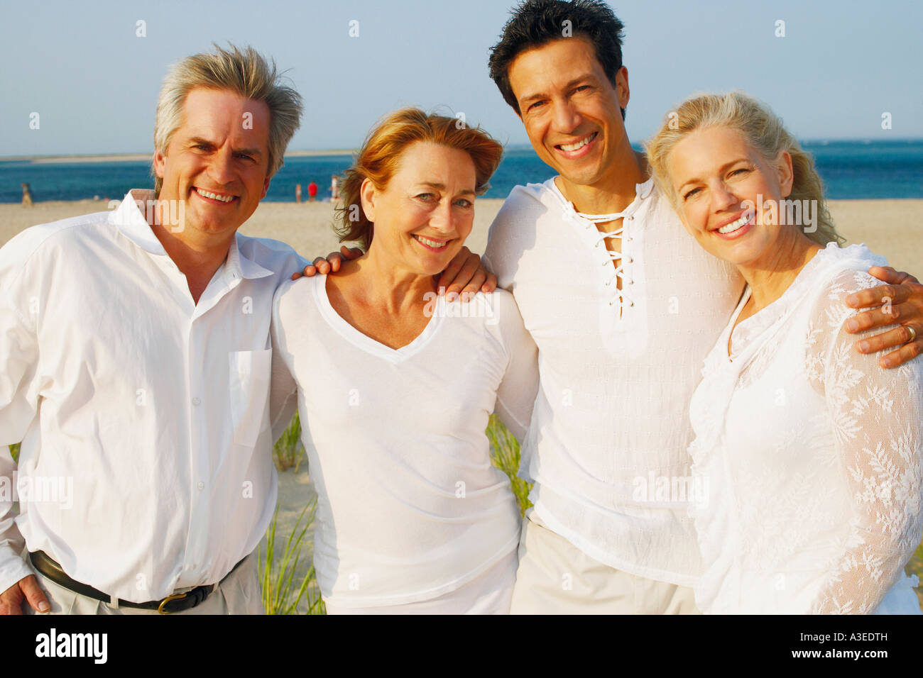 Porträt von zwei ältere Ehepaare stehen mit ihre Arme umeinander am Strand Stockfoto