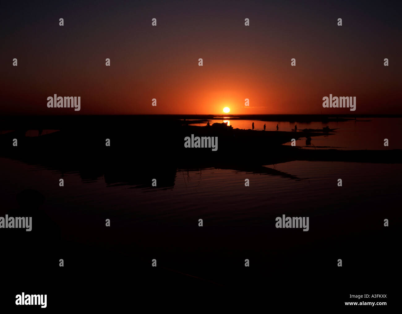 Die Sonne versinkt hinter einem kleinen Boot, einer Pinasse auf dem Fluss Niger in Mali Stockfoto