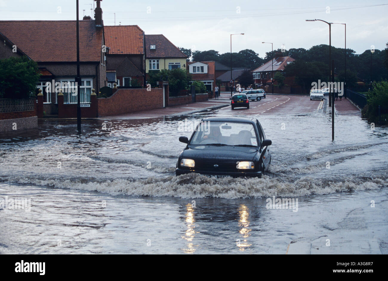 Ein kleines Auto fährt durch überfluteten Straße in Stadt Straße nach einem Gewitter in Sunderland, England Stockfoto