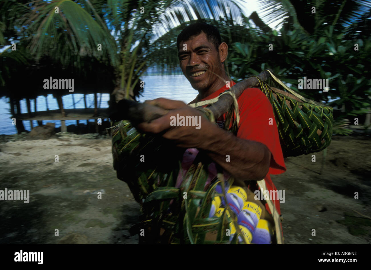 Ein Mann auf der Insel Manono Samoa trägt Haushaltswaren e g Dosen Fisch in Palm Leaf Körben aufgehängt an einem Mast über seine Schulter Stockfoto