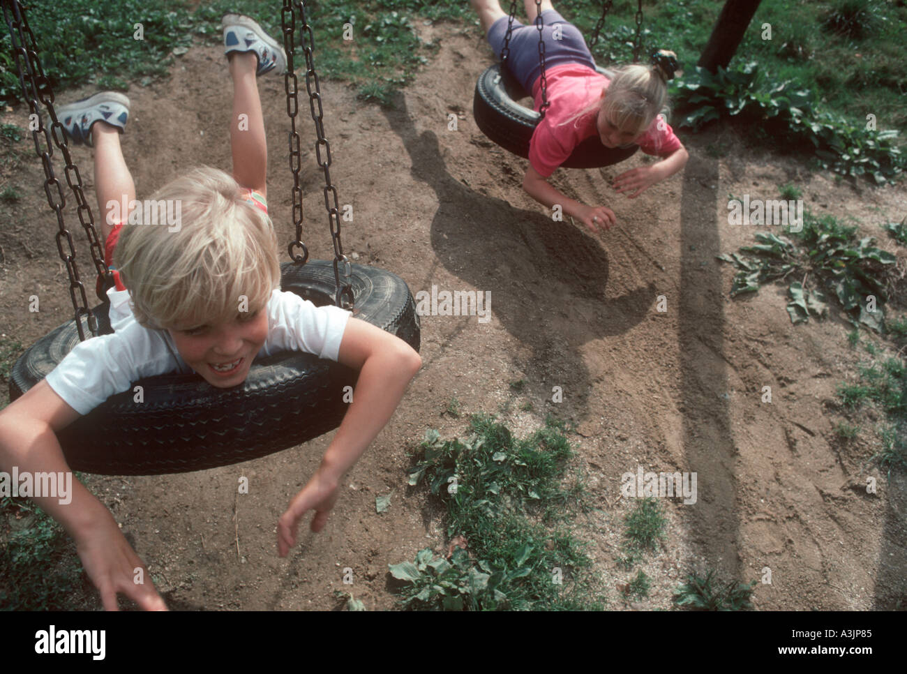 Blonder Junge und Mädchen schwingen auf Reifen, die auf dem Bauch liegend Stockfoto