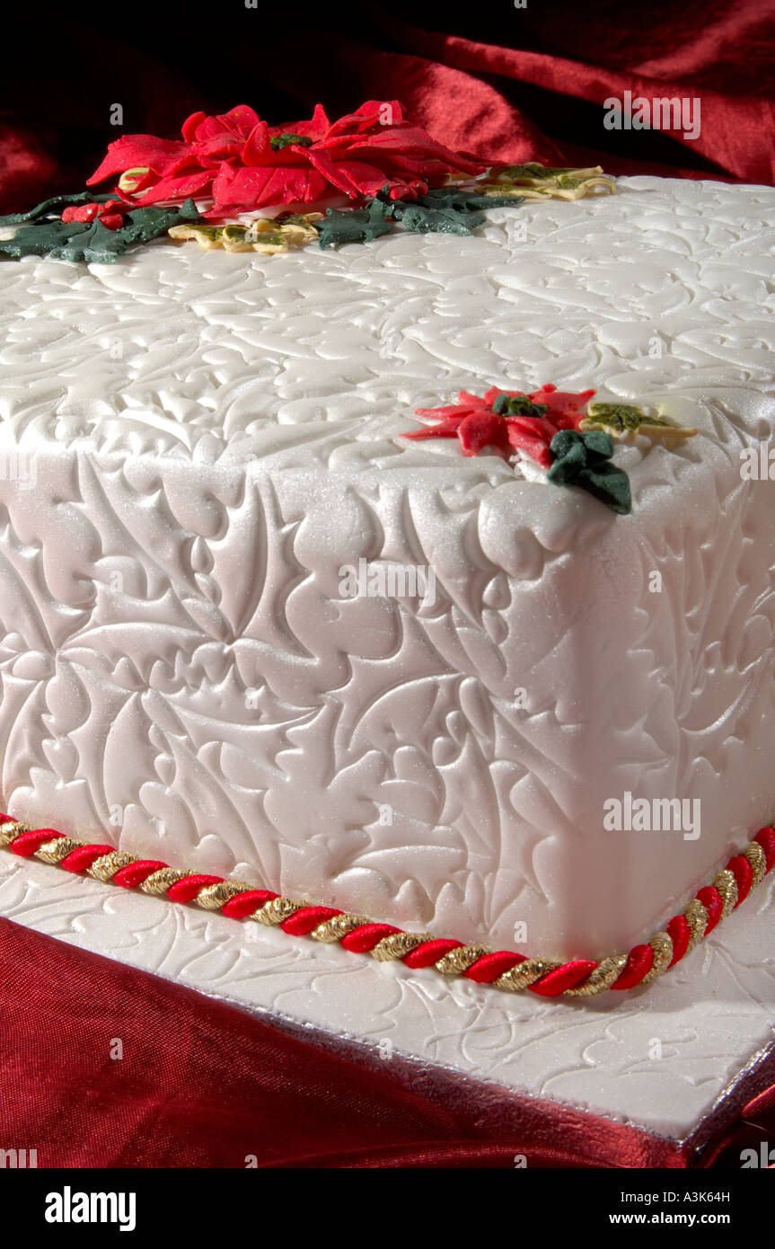 Wunderschön dekoriert Geeiste Frucht Weihnachtskuchen mit geprägtem Holly Blättern und roten Weihnachtsstern-Blüten aus Zuckerguss gemacht Stockfoto