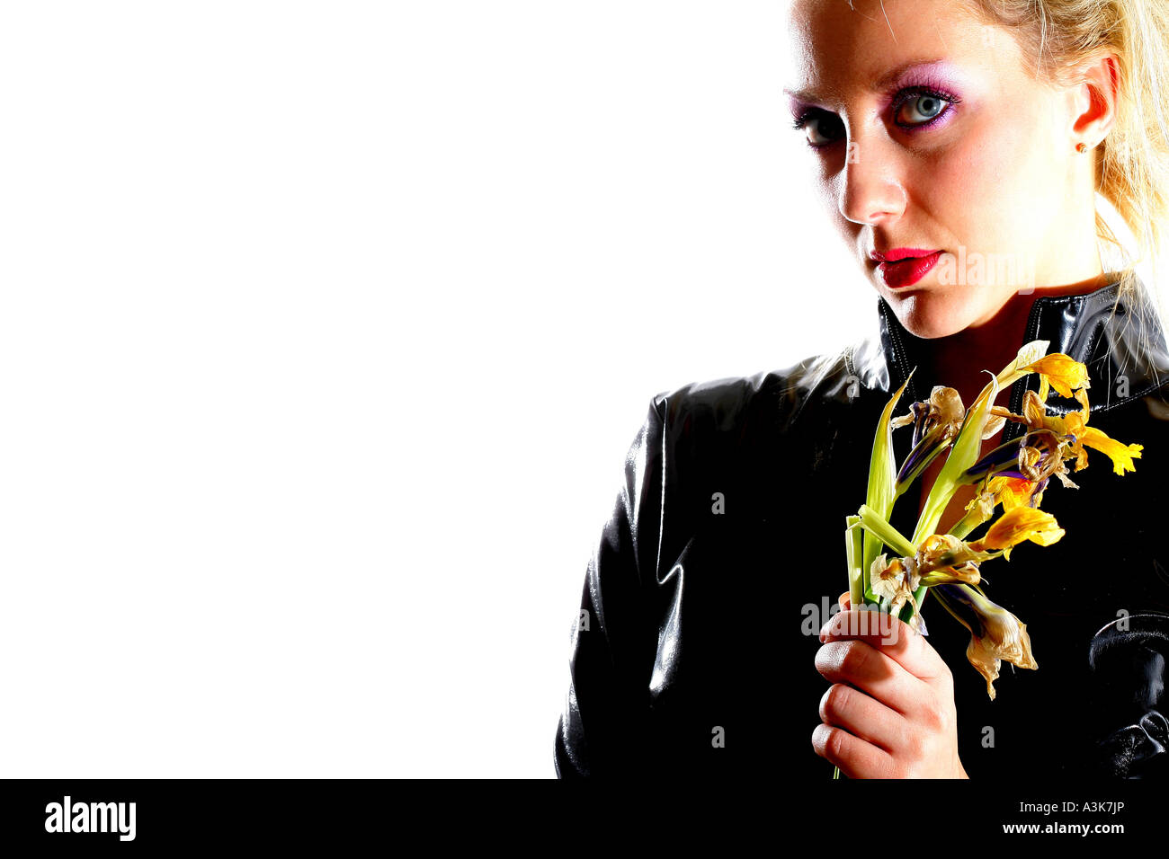 Störend oder gestörte junge Frau in schwarzes Leder gekleidet, hält ein Bündel von toten Blumen gegen einen weißen Hintergrund mit einen Freistellungspfad isoliert Stockfoto