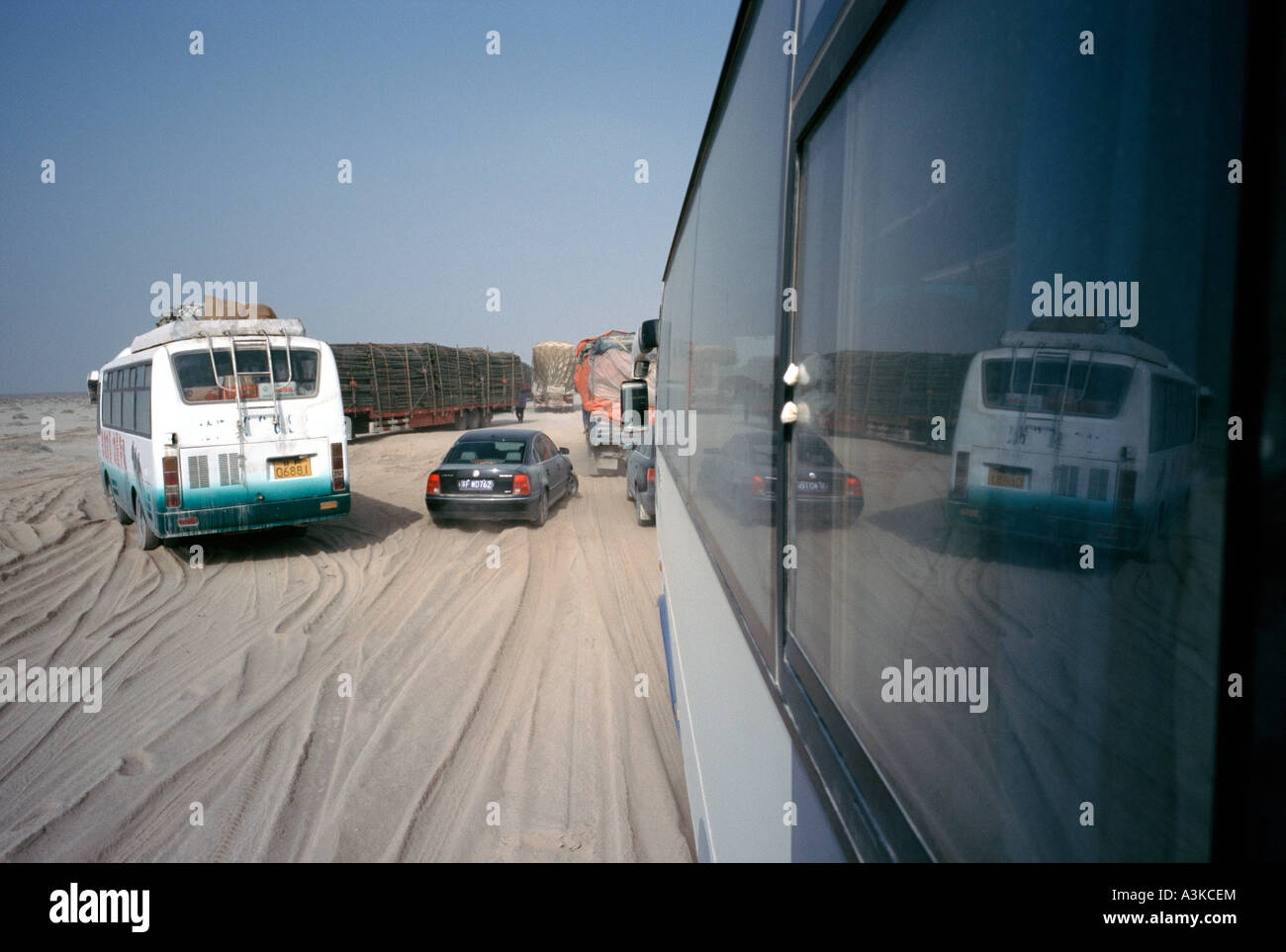 Verkehr in der Wüste neben einer Autobahn im Bau in der südlichen Wüste Gobi in der chinesischen Provinz Gansu. Stockfoto