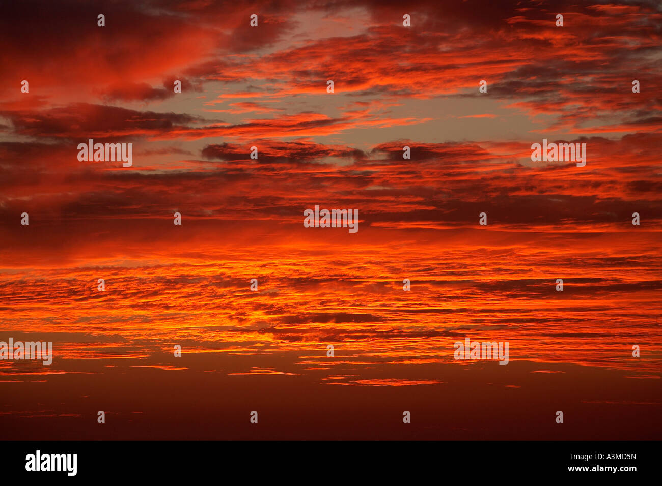 Eine dunkle, launisch, orange Wolkengebilde bei Sonnenuntergang mit einer Horizontlinie des Ozeans an der Unterseite des Rahmens. Stockfoto