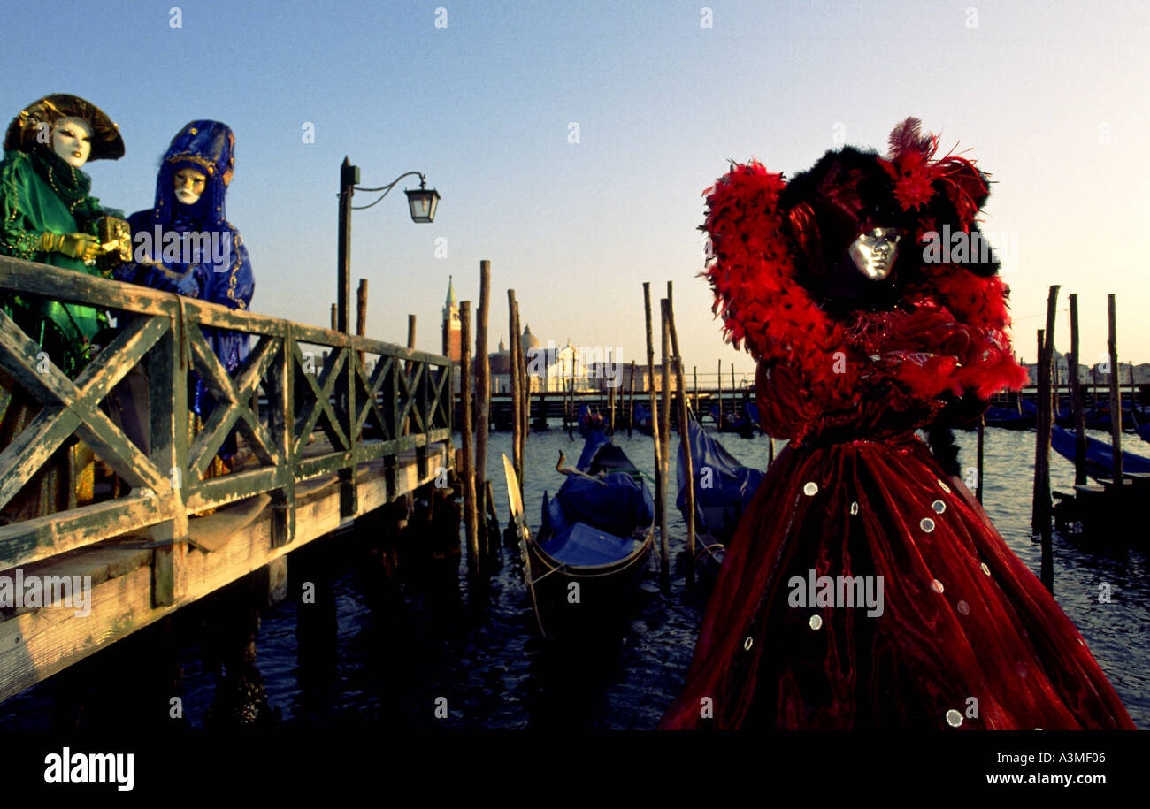 Zwei Personen auf einem kleinen Pier über Canal gekleidet in aufwendigen Kostümen und Masken für den jährlichen Maskerade-Karneval in Venedig Stockfoto