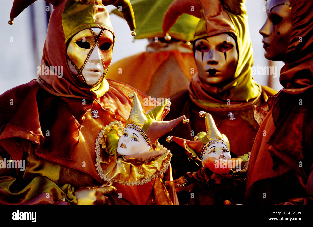 Zwei Personen gekleidet in leuchtend rot gold Jester Kostüme und Masken für den jährlichen Maskerade-Karneval in Venedig Italien Stockfoto
