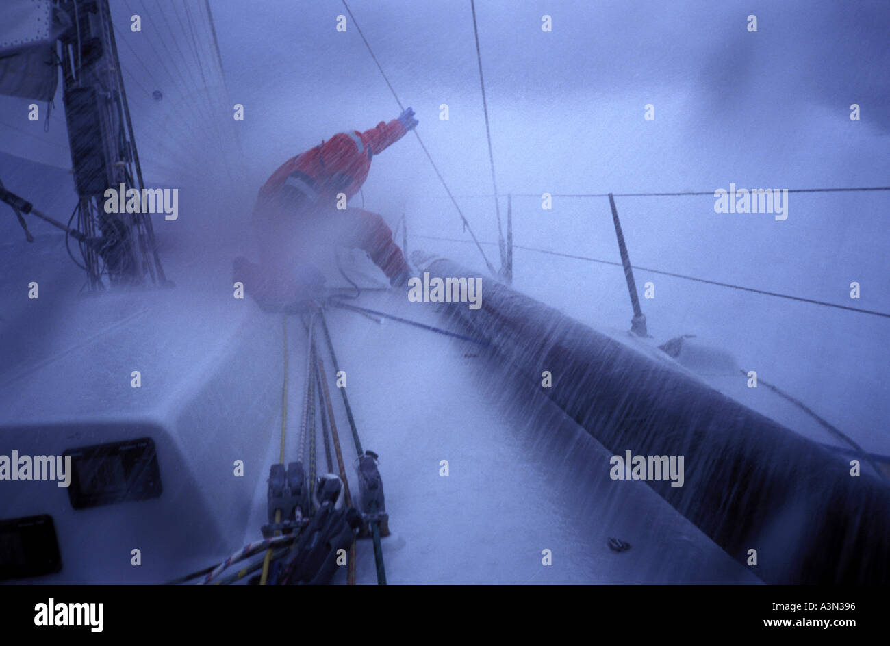 Mann kämpft mit dem Segel an Bord racing Yacht Rough Seas Stockfoto