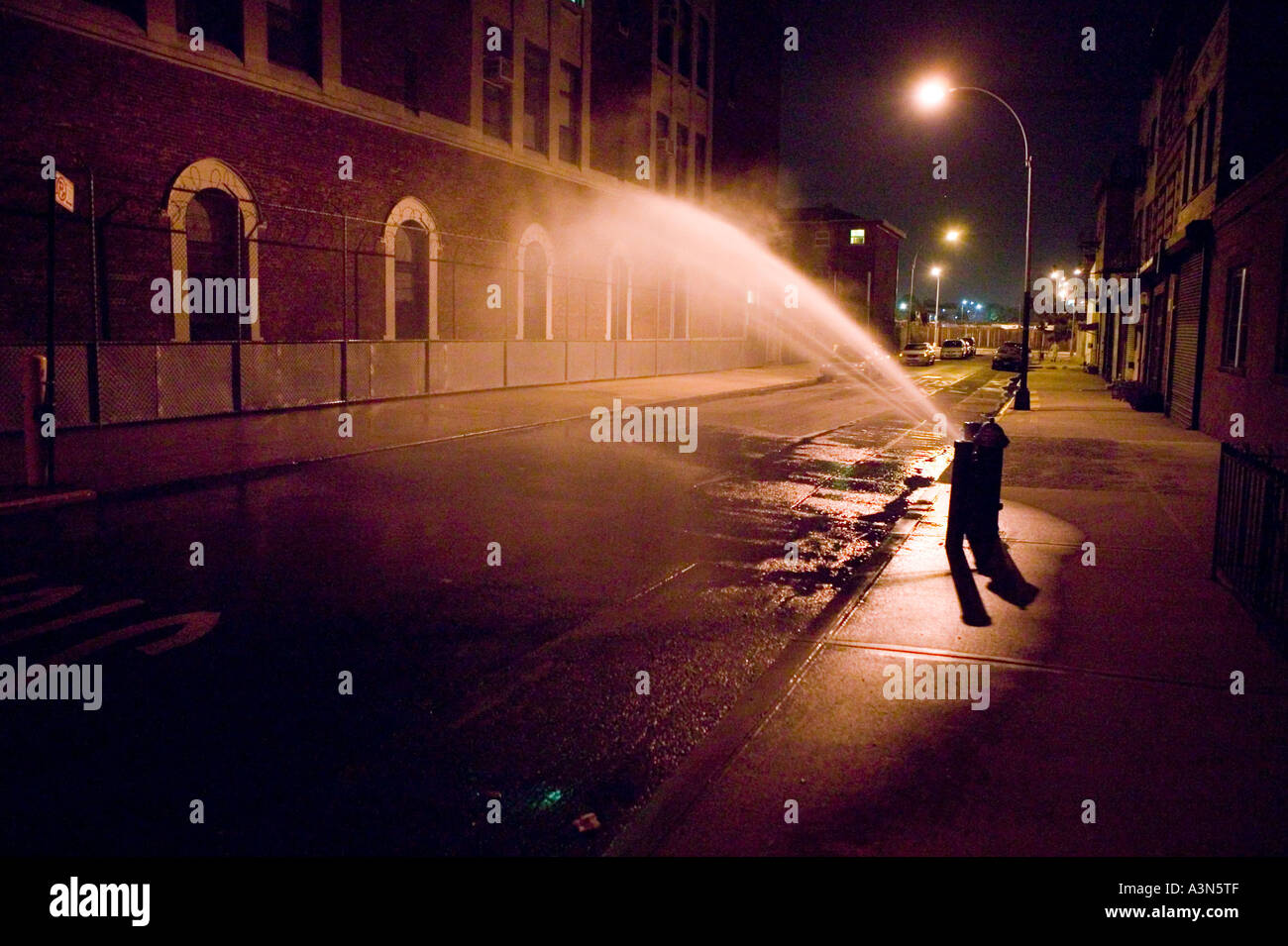 Einer offenen Hydranten sprüht eine Straße in Brooklyn New York City USA auf eine heiße Sommernacht Juli 2005 Stockfoto