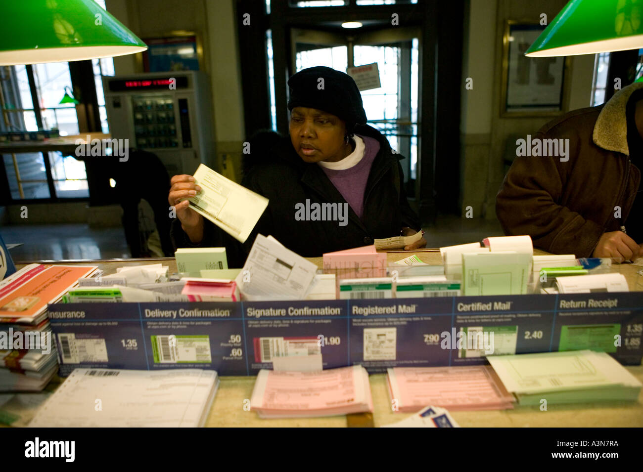 Eine Frau wählt zwischen Aufkleber und Etiketten auf einem Tisch an der James A Farley Post Office Gebäude an der 8. Avenue in New York City Stockfoto