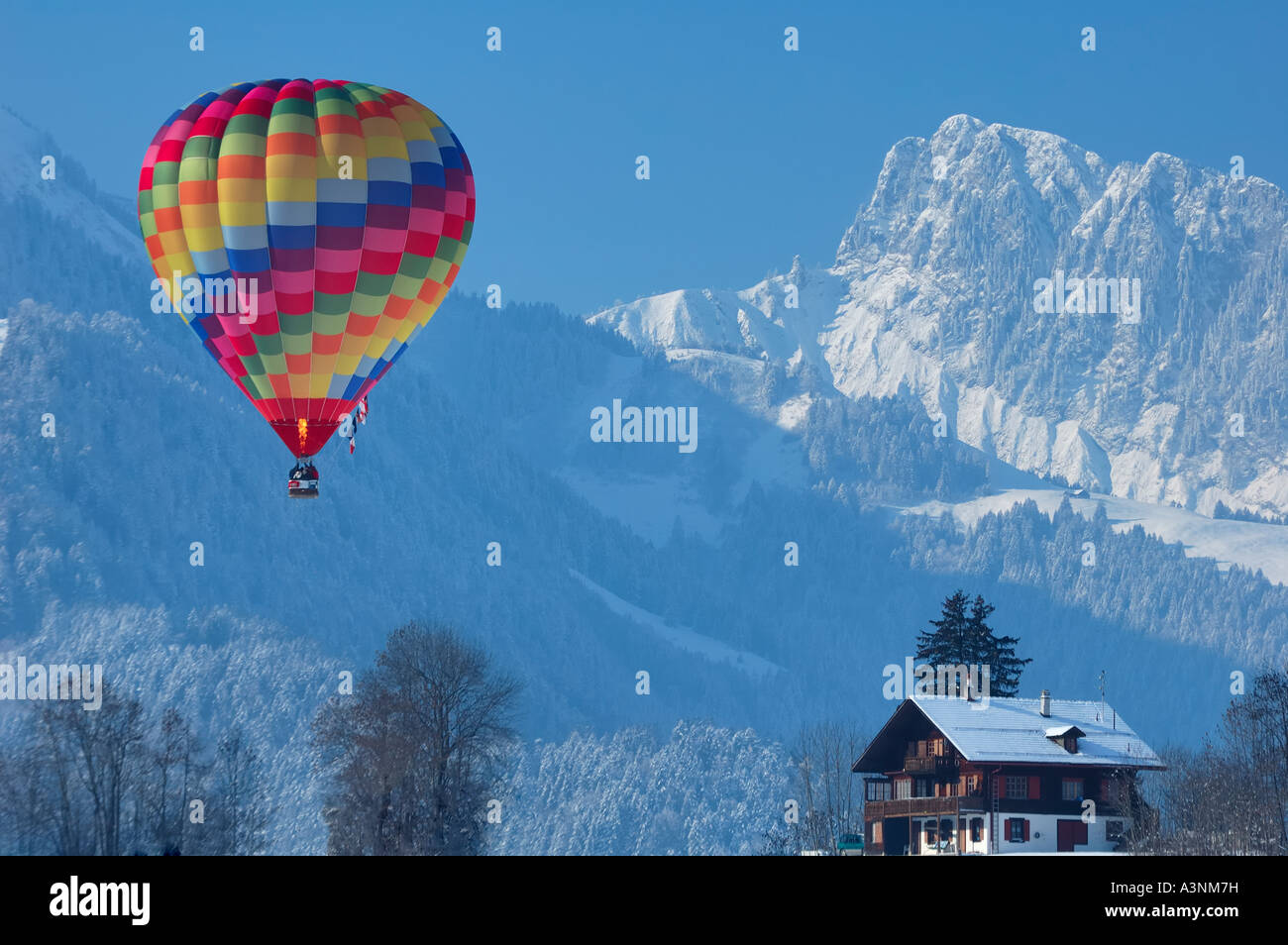 Ein Ballon fliegt durch die Schweizer Alpen in Chateau d ' Oex, Überfahren eines typischen Schweizer Chalets Stockfoto