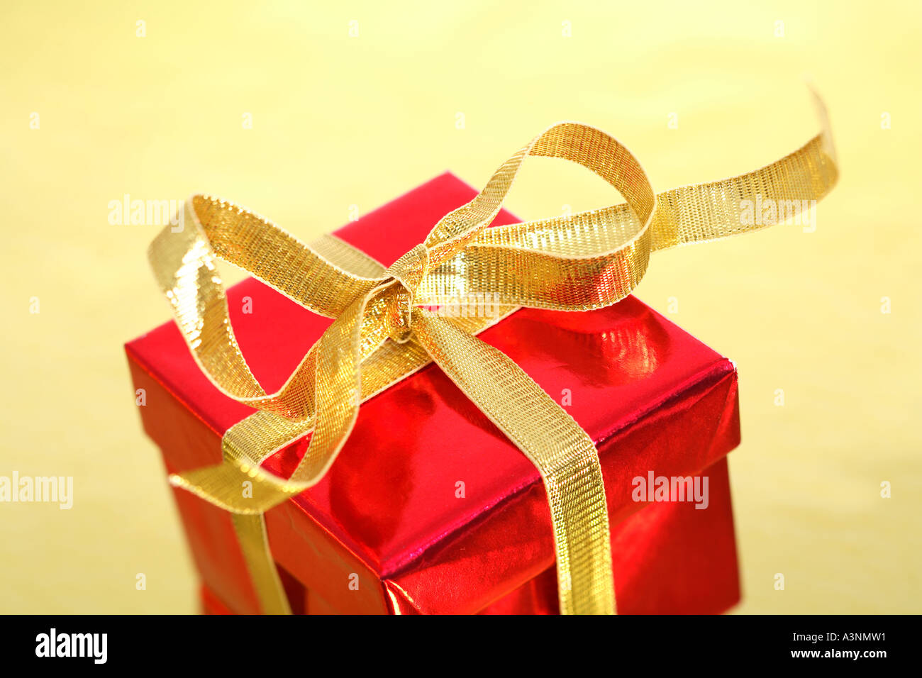 Red Christmas Present mit gold Bogen auf goldenem Hintergrund Stockfoto