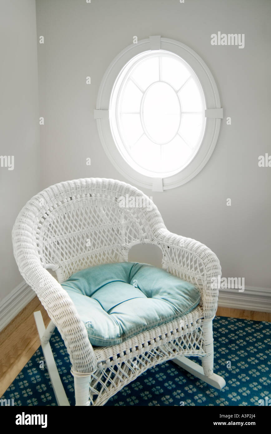 Weißer Schaukelstuhl Rattan Peddigrohr und ovale Fenster mit Sonnenschein Stockfoto