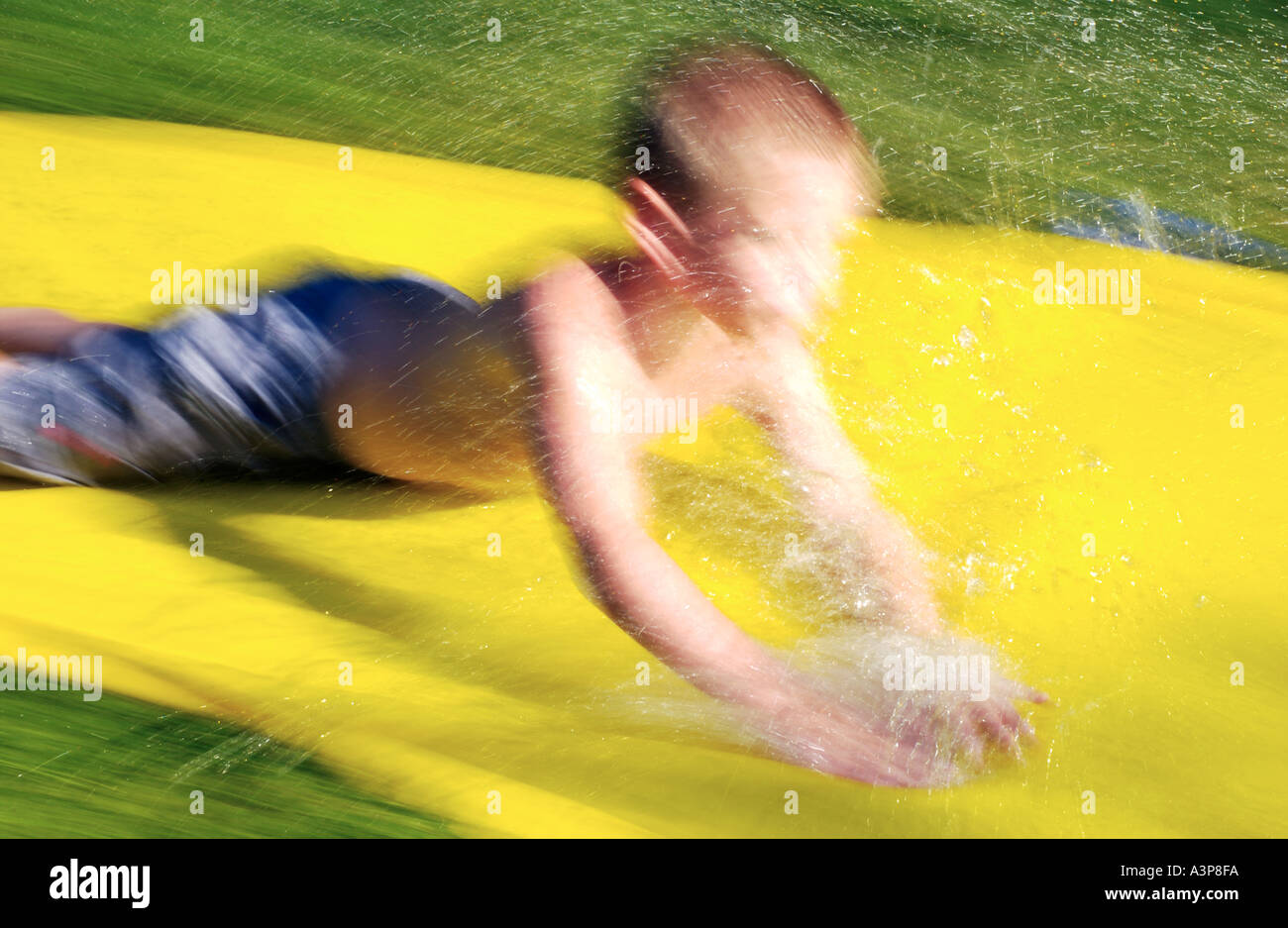 5 Jahre alter Junge auf Hinterhof Wasserrutsche gleiten Stockfoto