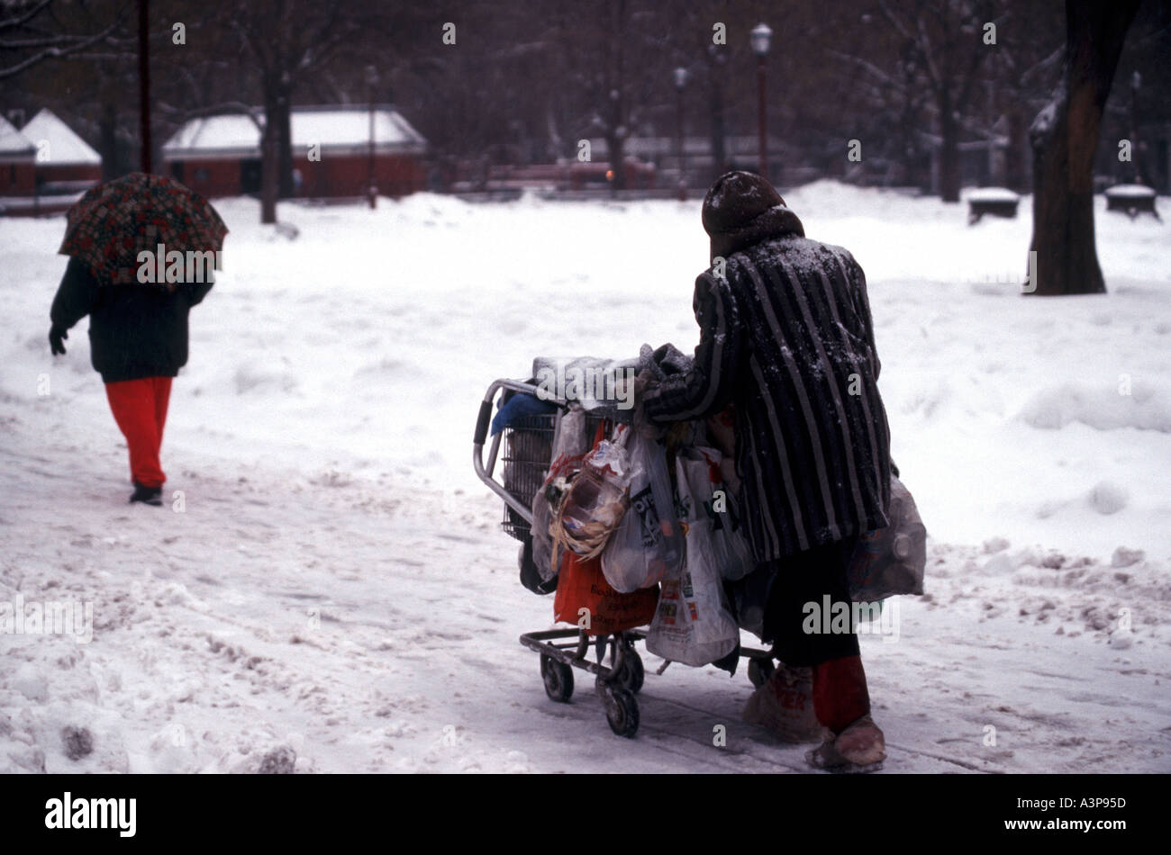 Ein Obdachloser Spaziergänge durch Washington Square Park mit ihren Habseligkeiten im Schnee Stockfoto