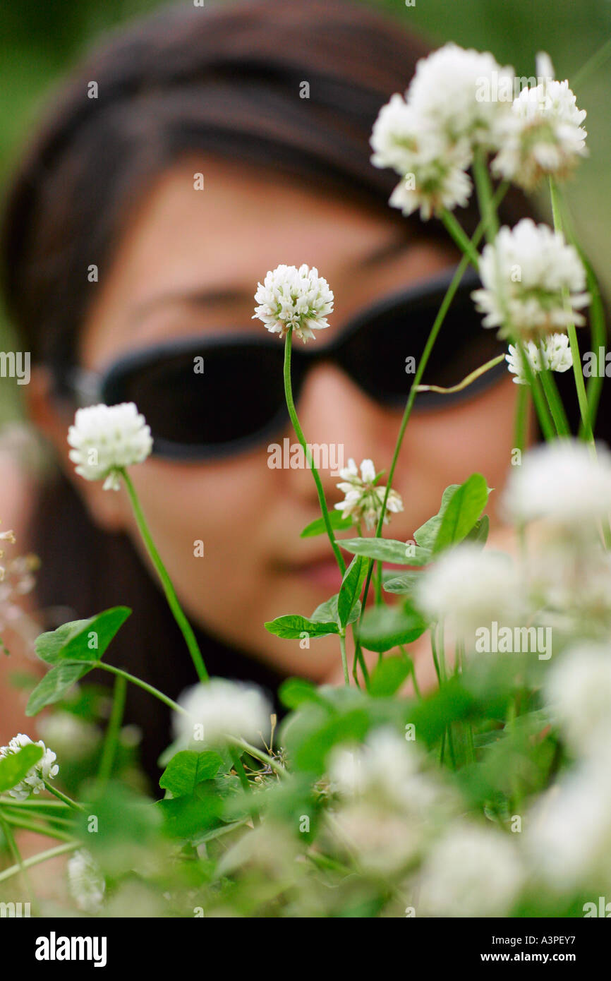 Junge Frau betrachtet durch Klee Blumen, New York City, New York, USA Stockfoto