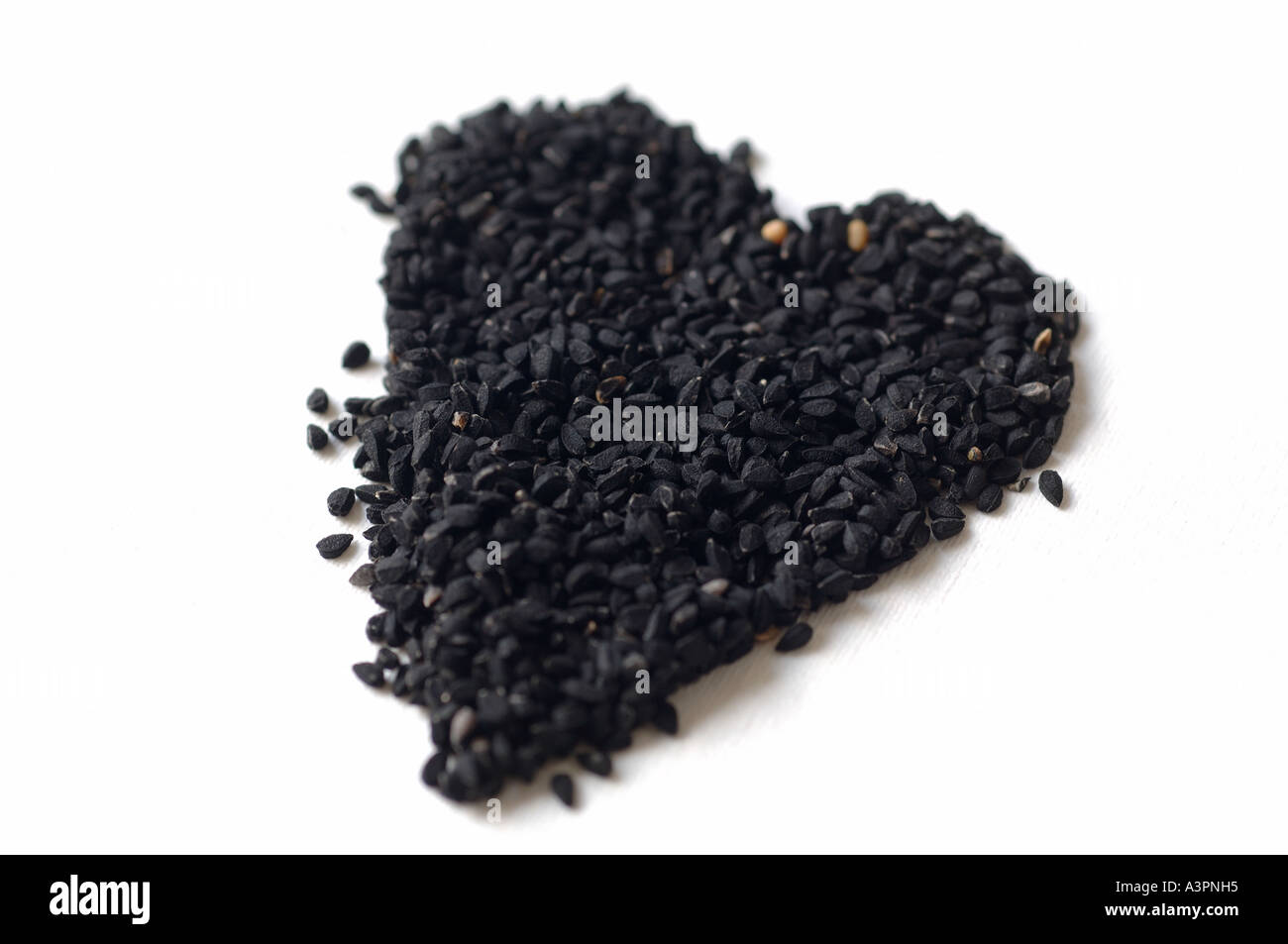 Schwarze Zwiebelsamen geformt wie ein Herz auf weißem Hintergrund Stockfoto