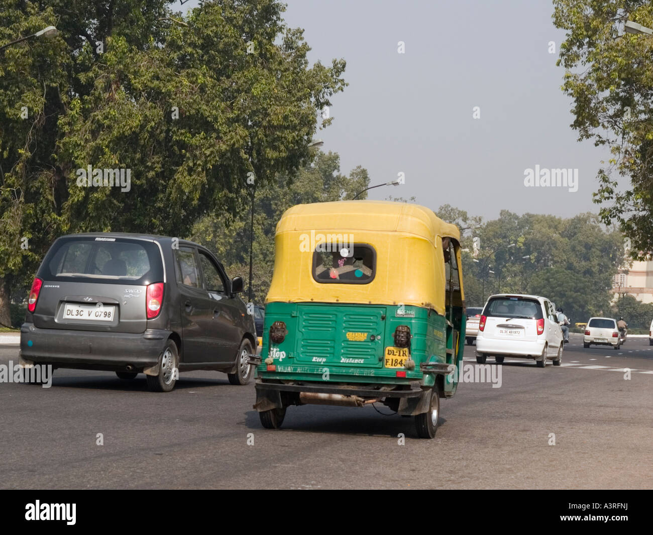 Verkehr auf der viel befahrenen Straße mit grünen und gelben Autorikscha angeheizt durch komprimiertes Erdgas CNG New Delhi Uttar Pradesh, Indien Stockfoto