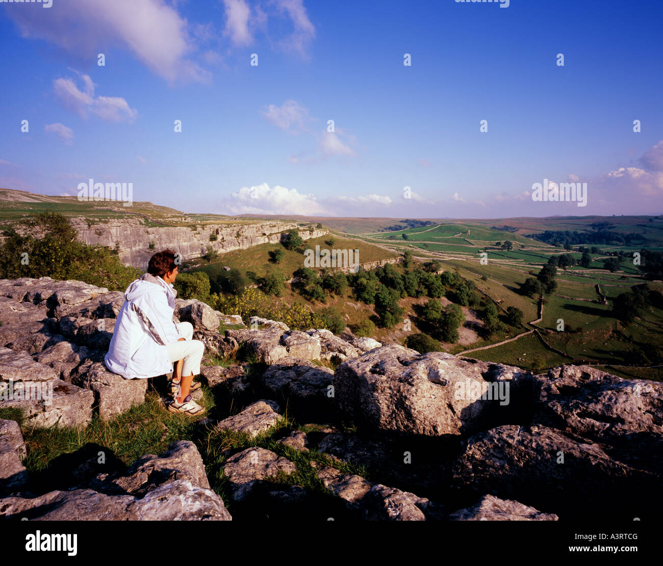 Frau, bewundern Sie die Aussicht von der Spitze des Malham Cove am späten Nachmittag Sonne Dale Yorkshire, England, UK. Stockfoto