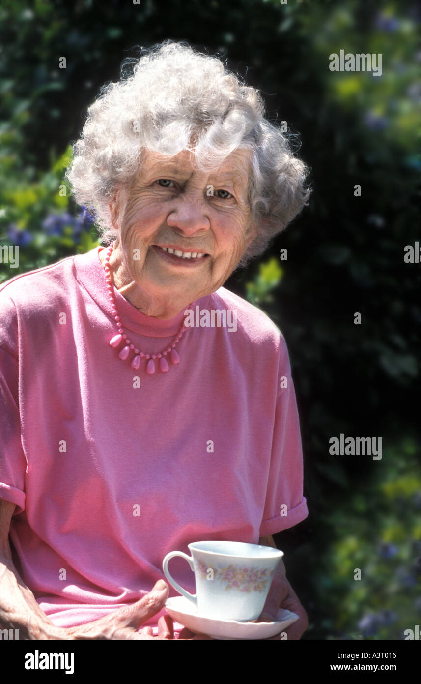 Neunzig Jahre alte Engländerin, die mit einer Tasse Tee in ihrem Garten Stockfoto