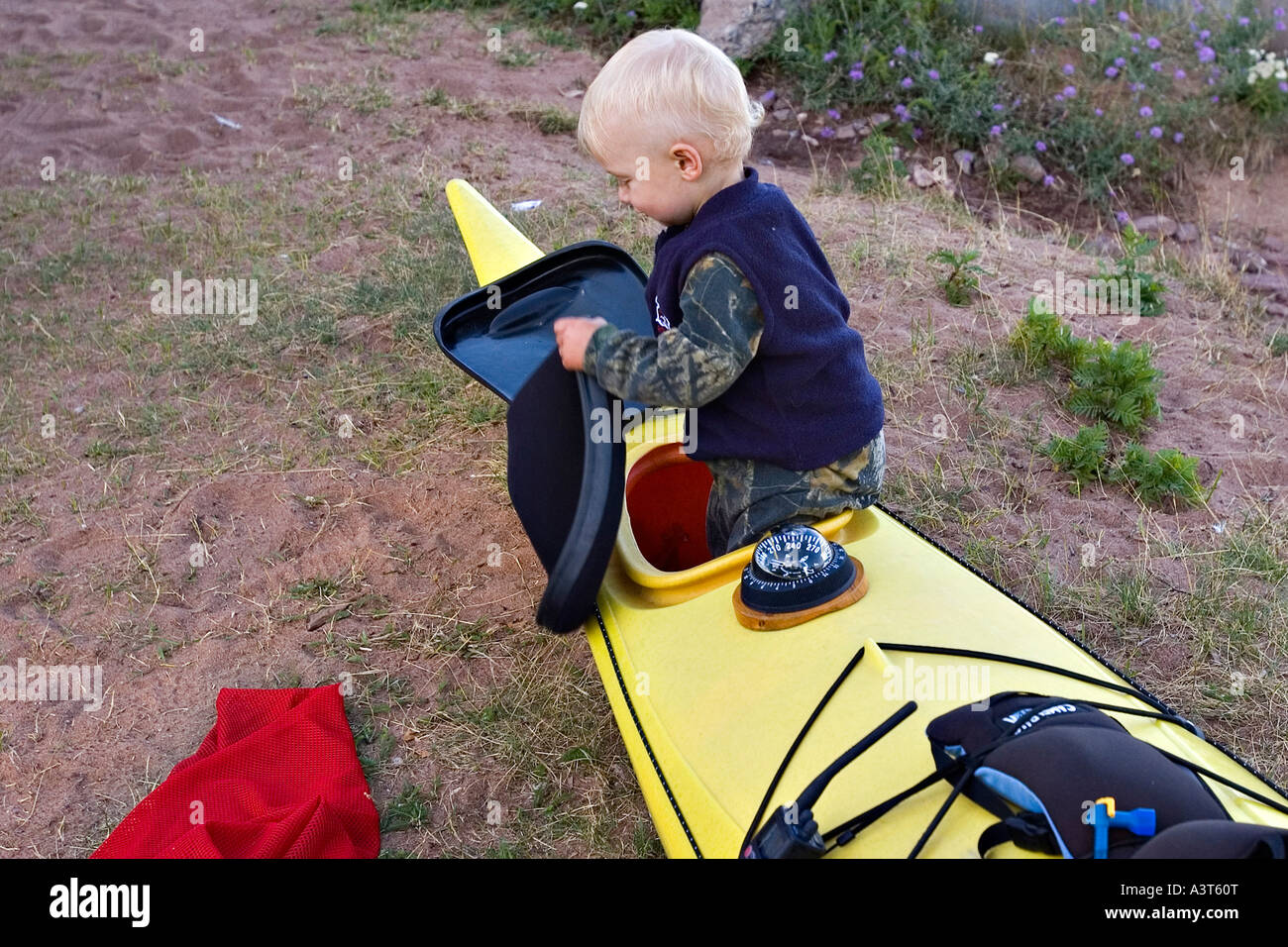 Ein Kleinkind nimmt die vordere Luke ein Seekajak, während seine Eltern vorbereiten zu paddeln am Lake Superior in der Nähe von Marquette, Michigan Stockfoto