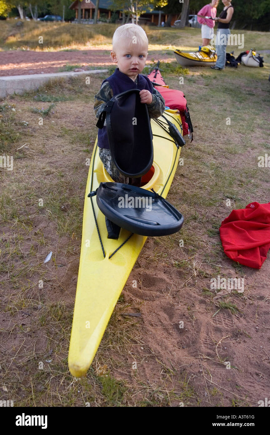 Ein Kleinkind nimmt die vordere Luke ein Seekajak, während seine Eltern vorbereiten zu paddeln am Lake Superior in der Nähe von Marquette, Michigan Stockfoto