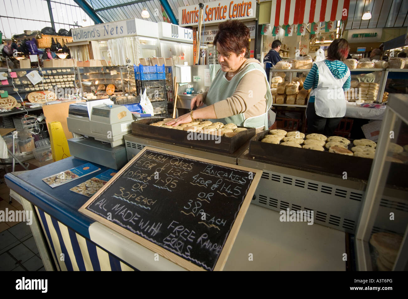 Frau Standbesitzer Kochen frisch gemacht Kuchen gekocht wird auf einem warmen Teller Bratpfanne an der Markthalle Swansea West Glamorgan Welsch Stockfoto