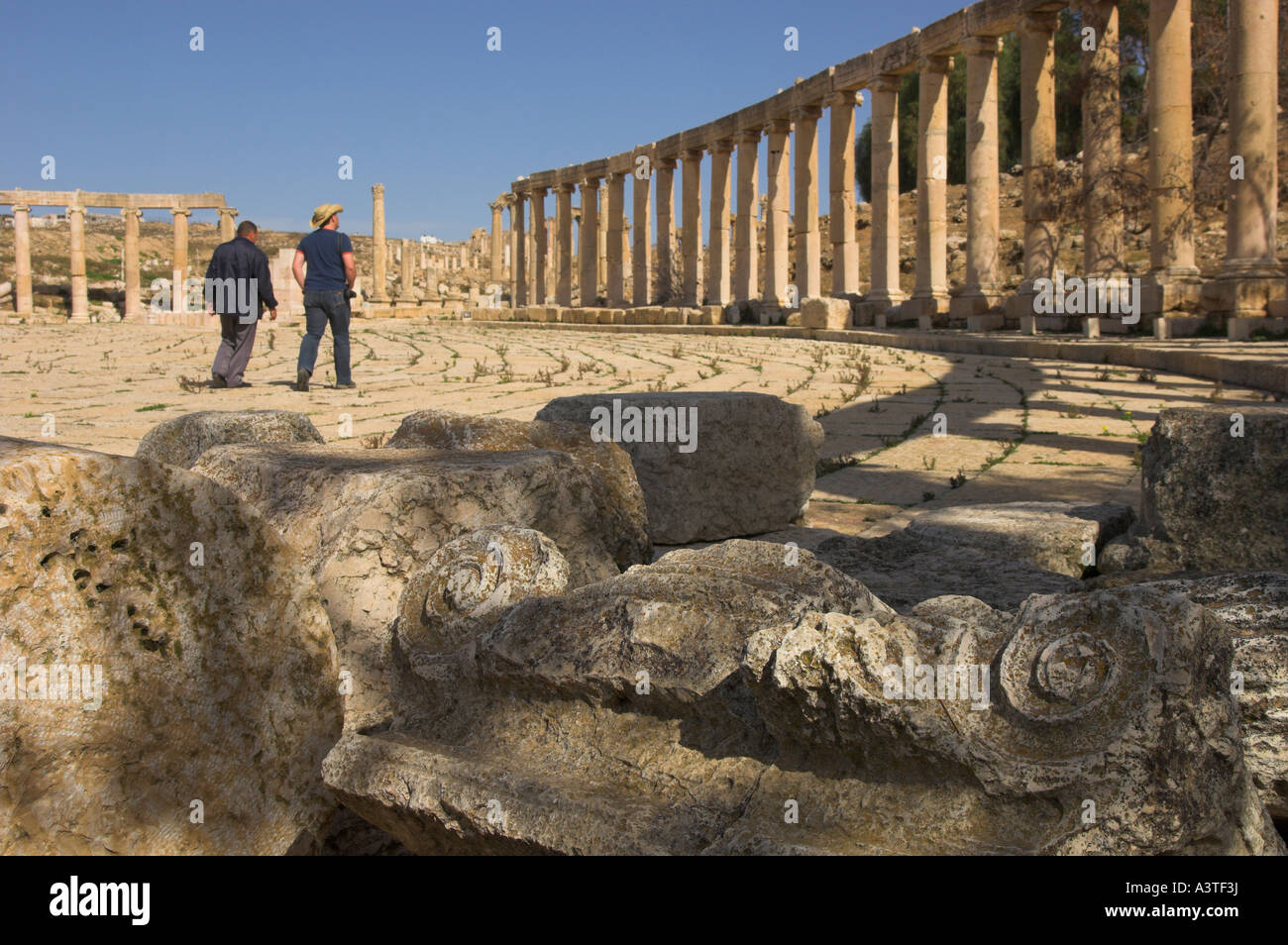 Jordan Jerash Ausgrabungsstätte Forum Ansicht mit Spalte Kapital in Frgd und Besucher, die im Forum bkgd Stockfoto
